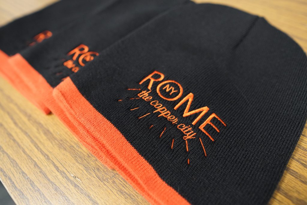 Black and orange beanies with the words Rome, NY, The Copper City
